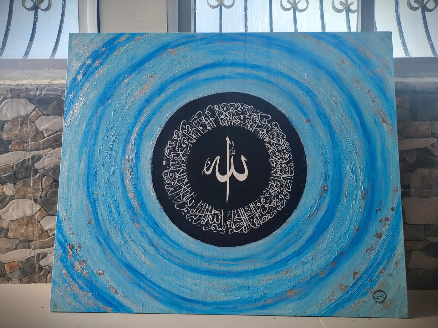 A swirling blue painted vortex with silver calligraphy at its still center