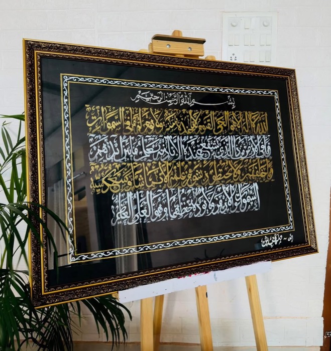 Silver and gold calligraphy on black, on an easel