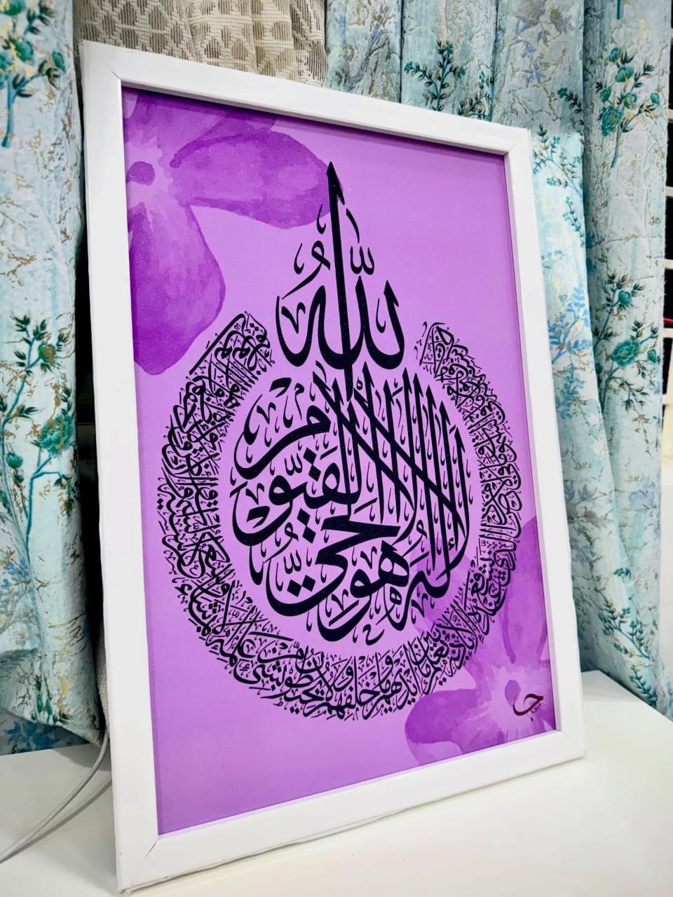Ayat al-Kursi in black script on a lilac ground with soft violet blossoms, white frame