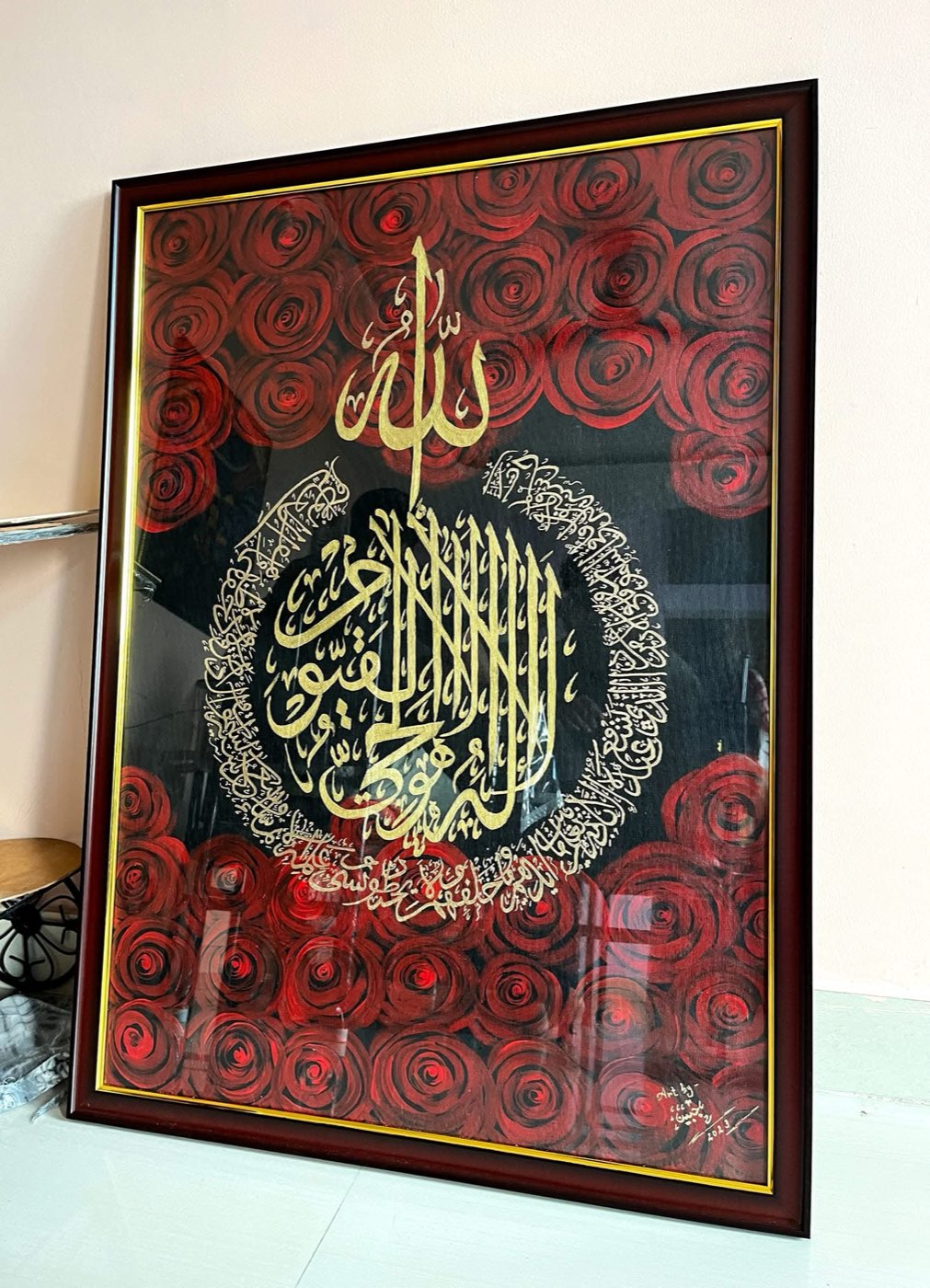 Gilded circular composition on black surrounded by deep red painted roses, dark frame