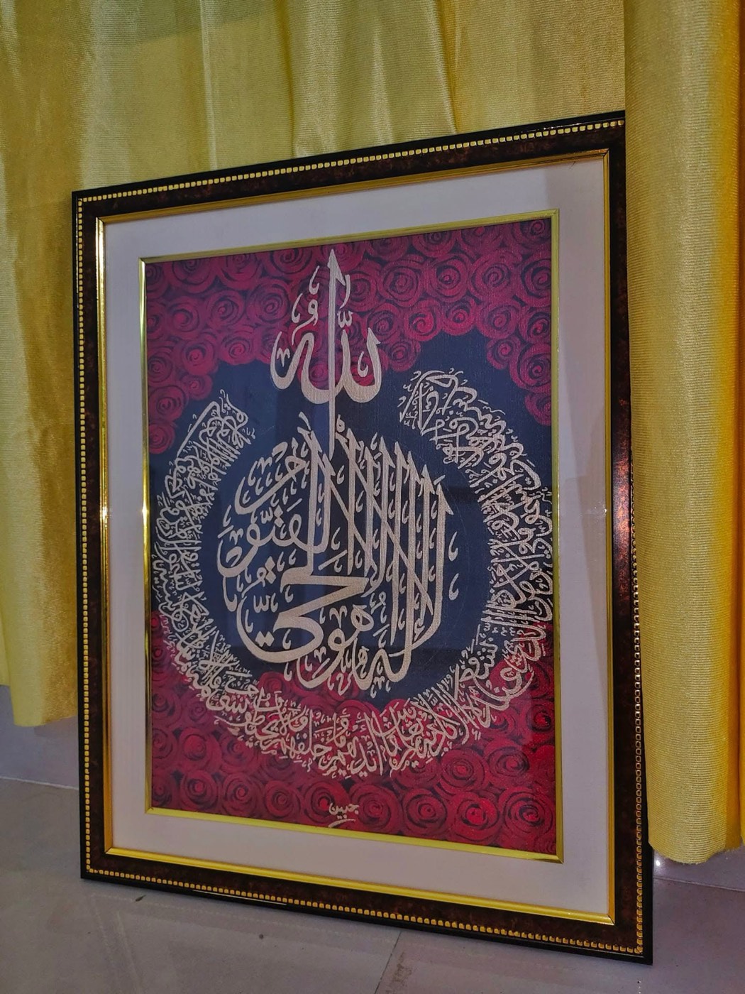 Silver calligraphy roundel over a magenta damask-patterned ground, gilt-edged black frame