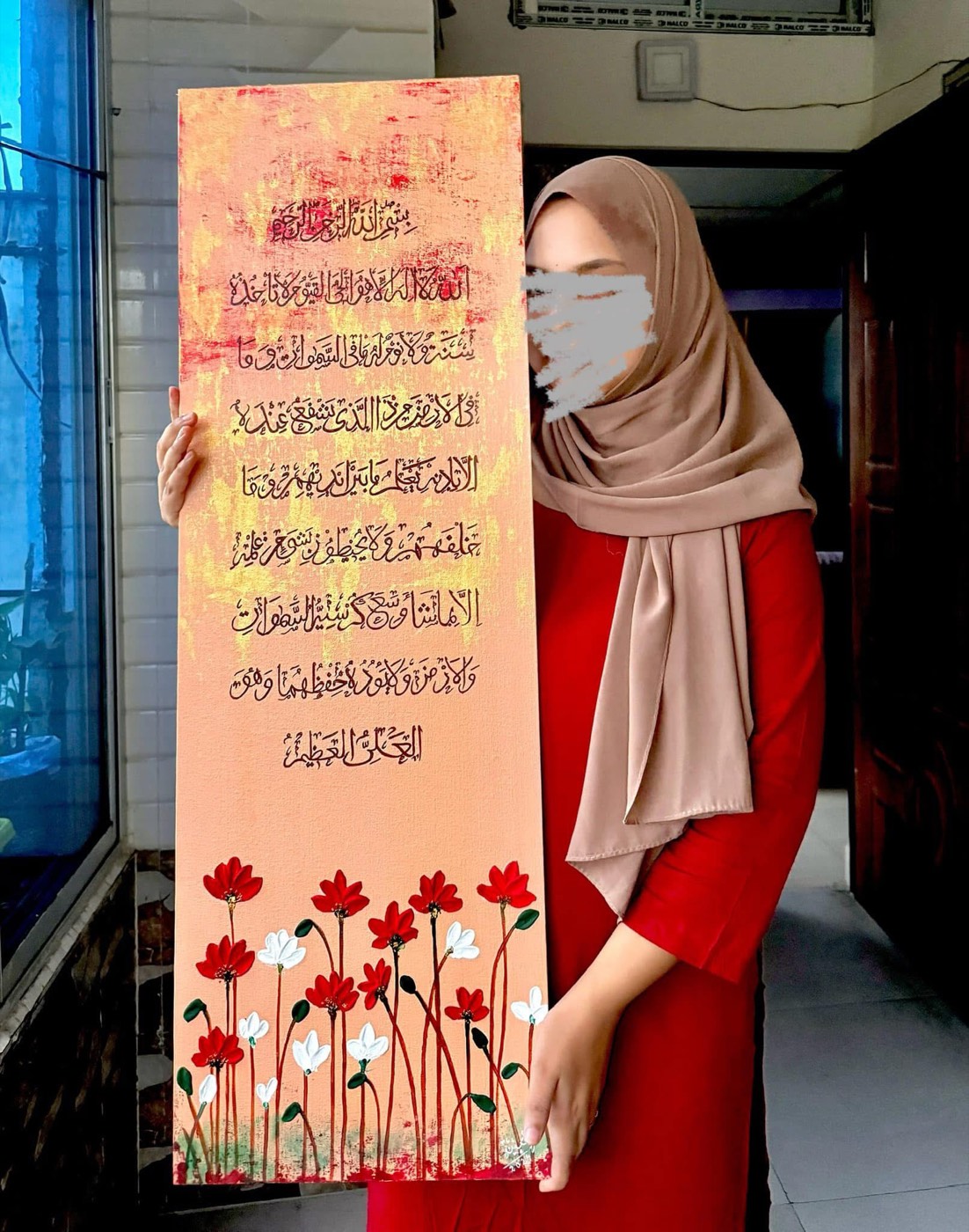 Tall coral canvas of Ayat al-Kursi with red poppies painted along the base, held by the artist