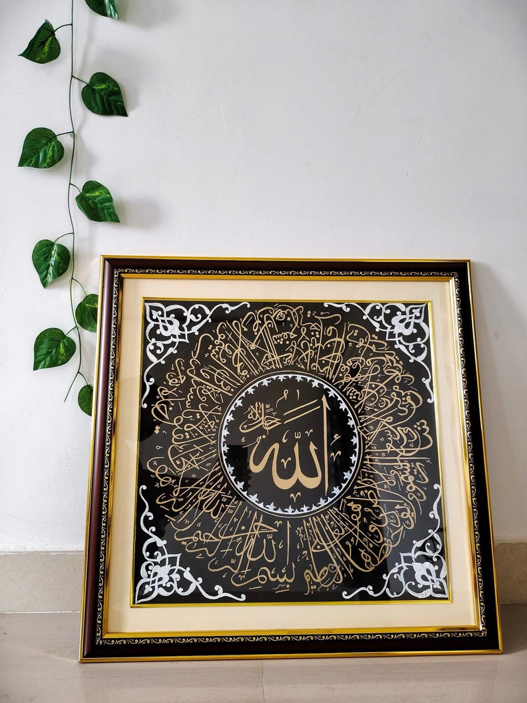 Square black painting with gold and silver circular calligraphy and corner ornaments in ornate frame