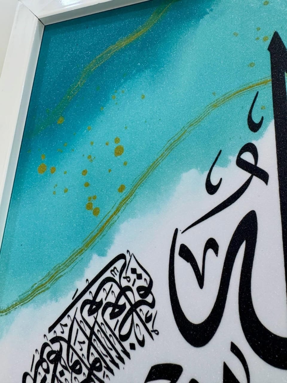 Detail of black calligraphy strokes over a turquoise wash with gold speckles