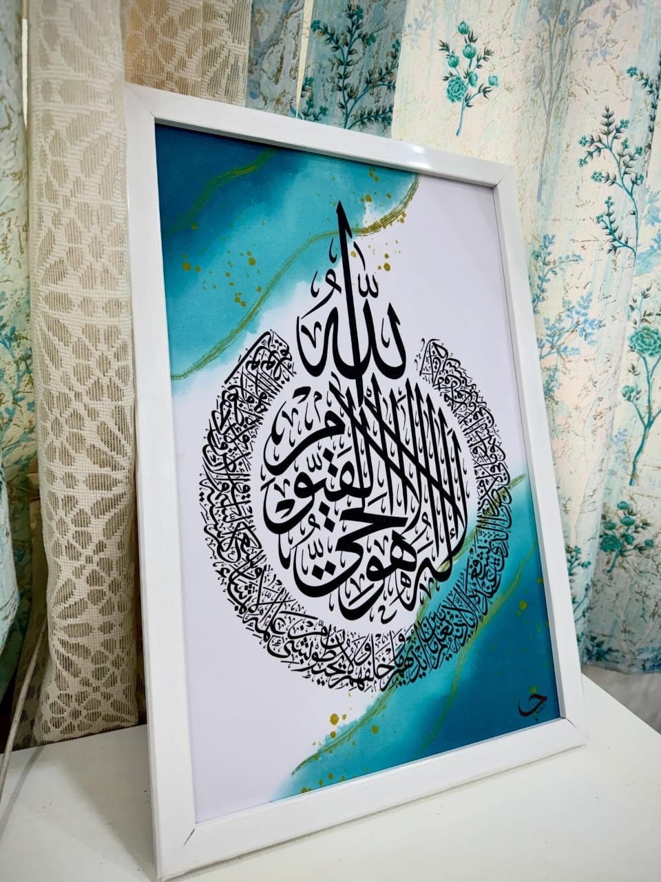 Ayat al-Kursi in black thuluth over a turquoise wash with gold veining, in a white frame